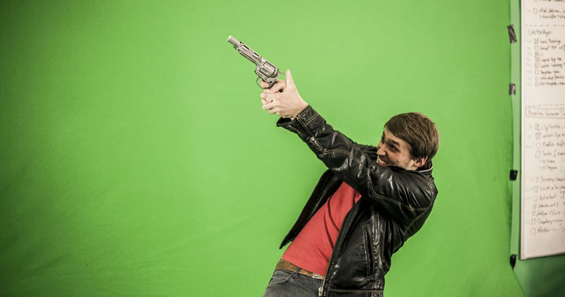 Mann steht mit Waffe vor dem Greenscreen